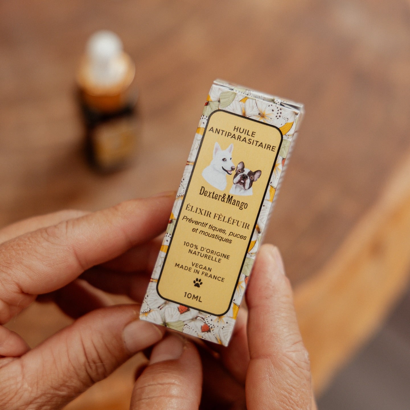 Boîte élégante de la lotion antiparasitaire pour chien, tenue dans une main pour illustrer son format pratique et éco-friendly. Un produit respectueux de l'environnement, pensé pour protéger votre chien des parasites tout en prenant soin de sa peau et de la planète.